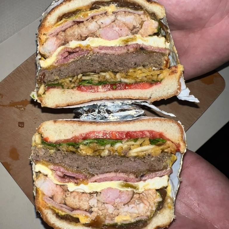 A Combo Hamburguesa cut in half, showing the fried egg, beef patty, chicken and potato sticks stacked inside